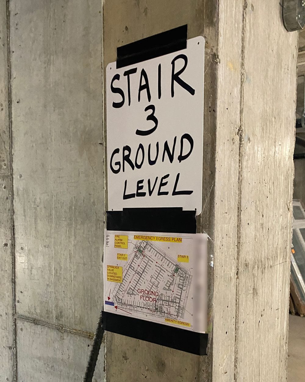 Emergency egress plan taped below a Stair 3 Ground Level sign on a concrete column